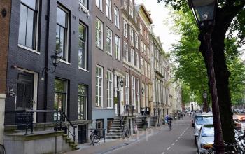 Exterior view of Herengracht 420 in Amsterdam Canal Belt, showcasing classic canal houses and the street with parked bicycles.