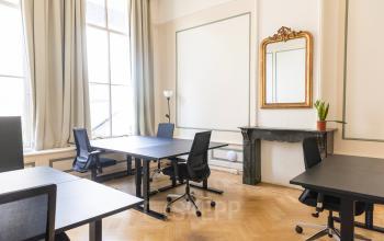 Bright office space rental at Herengracht 420, Amsterdam Canal Belt, featuring wooden floors, large windows, desks, office chairs, a marble fireplace, and a decorative mirror.