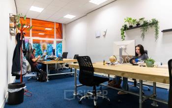 Office space to rent at Herengracht 420, Amsterdam Canal Belt, with multiple workstations, plants, and natural light from large windows.