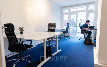 Office space rental at Herengracht 420, Amsterdam Canal Belt, featuring desks, chairs, indoor plants, and a person working on a laptop.