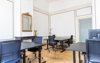 Bright office space with sleek desks and chairs, mirrored wall and hardwood floors at Herengracht 420, Amsterdam Canal Belt.