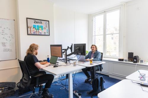 Two professionals working at desks with computers in a furnished office at Herengracht 420, Amsterdam Canal Belt, available for office space rental.