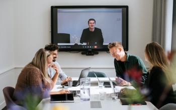 A vibrant office space in Amsterdam's Canal Belt at Keizersgracht 62-64, where professionals engage in a lively video conference, exemplifying an ideal office space rental.