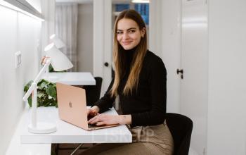 Businessperson working on a laptop in a bright office space with modern decor at Keizersgracht 62-64, a sought-after location in Amsterdam Canal Belt for office space rental.