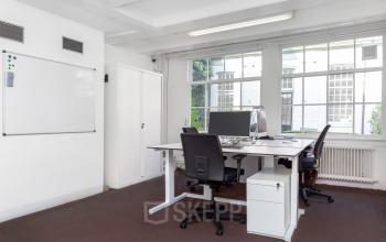 Bright office space with large windows, furnished with desks and chairs, ideal for office space rental at Keizersgracht 62-64 in Amsterdam Canal Belt.