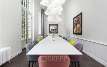 Bright, modern office space rental with a long table and colorful chairs, located at Keizersgracht 62 – 64, Amsterdam Canal Belt.