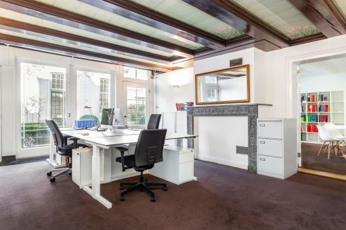 Bright office space with desks, chairs, and a view of the garden, suitable for rent office space at Keizersgracht 62-64, Amsterdam Canal Belt.