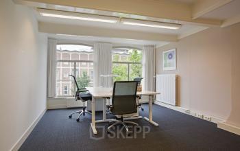 Contemporary office space rental at Herengracht 282, featuring a well-lit room with desks, chairs, and a view of Amsterdam's historic Canal Belt.