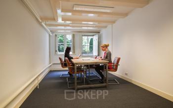 Professionals in a well-lit conference room exploring options for office space rental at Herengracht 282, Amsterdam Canal Belt.