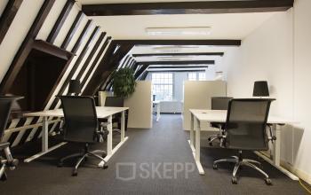 Chic canal-side Herengracht 282 office space rental in Amsterdam, featuring modern furnished workspaces with slanted beams and ample lighting.