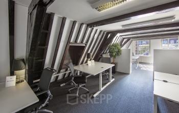 Office space rental at Herengracht 282, Amsterdam Canal Belt featuring modern desks under stylish sloping beams with ample natural light