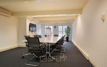 Modern conference room available for office space rental at Herengracht 282 in Amsterdam Canal Belt, equipped with a sleek table, chairs, and presentation screen.