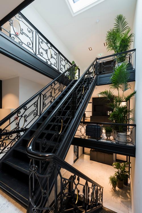 Spacious interior stairwell at Keizersgracht 121, Amsterdam. Elegant metal railings, natural light, and lush plants create a vibrant workspace environment. Ideal for office space rental in the Amsterdam Canal Belt.