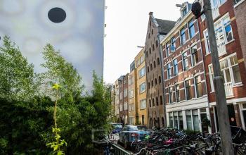 Exterior view of office buildings and residential apartments on Vinkenstraat 79 HS, in Amsterdam Canal Belt, with parked cars and bicycles.