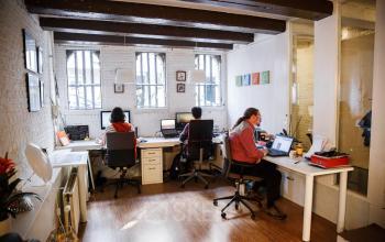 Office space rental at Vinkenstraat 79 HS in Amsterdam Canal Belt showing several people working at desks with computers under exposed beams.