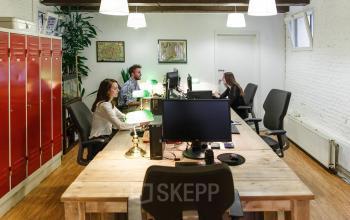 Office space for rent at Vinkenstraat 79 HS, Amsterdam Canal Belt, featuring wooden desks, ergonomic chairs, red lockers, and several professionals working at computers under modern lighting.