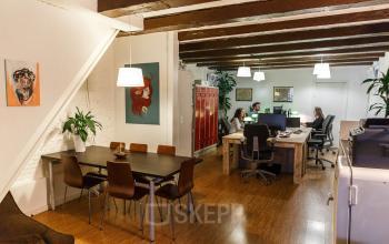 Office space rental at Vinkenstraat 79 HS in Amsterdam Canal Belt featuring wooden beams, modern furniture, and focused professionals at desks.