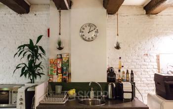 Office pantry at Vinkenstraat 79 HS in Amsterdam Canal Belt, featuring kitchen appliances, a clock, and a small potted plant.
