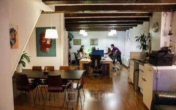 Office space rental at Vinkenstraat 79 HS in Amsterdam Canal Belt, showcasing a cozy workspace with wooden floors, multiple desks, and modern lighting.