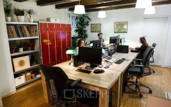 Interior of an office space rental at Vinkenstraat 79 HS, Amsterdam Canal Belt, with wooden desks, computers, office chairs, and three people working.