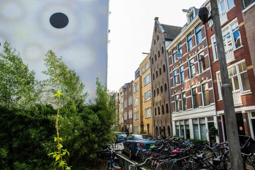 Exterior view of office buildings and residential apartments on Vinkenstraat 79 HS, in Amsterdam Canal Belt, with parked cars and bicycles.