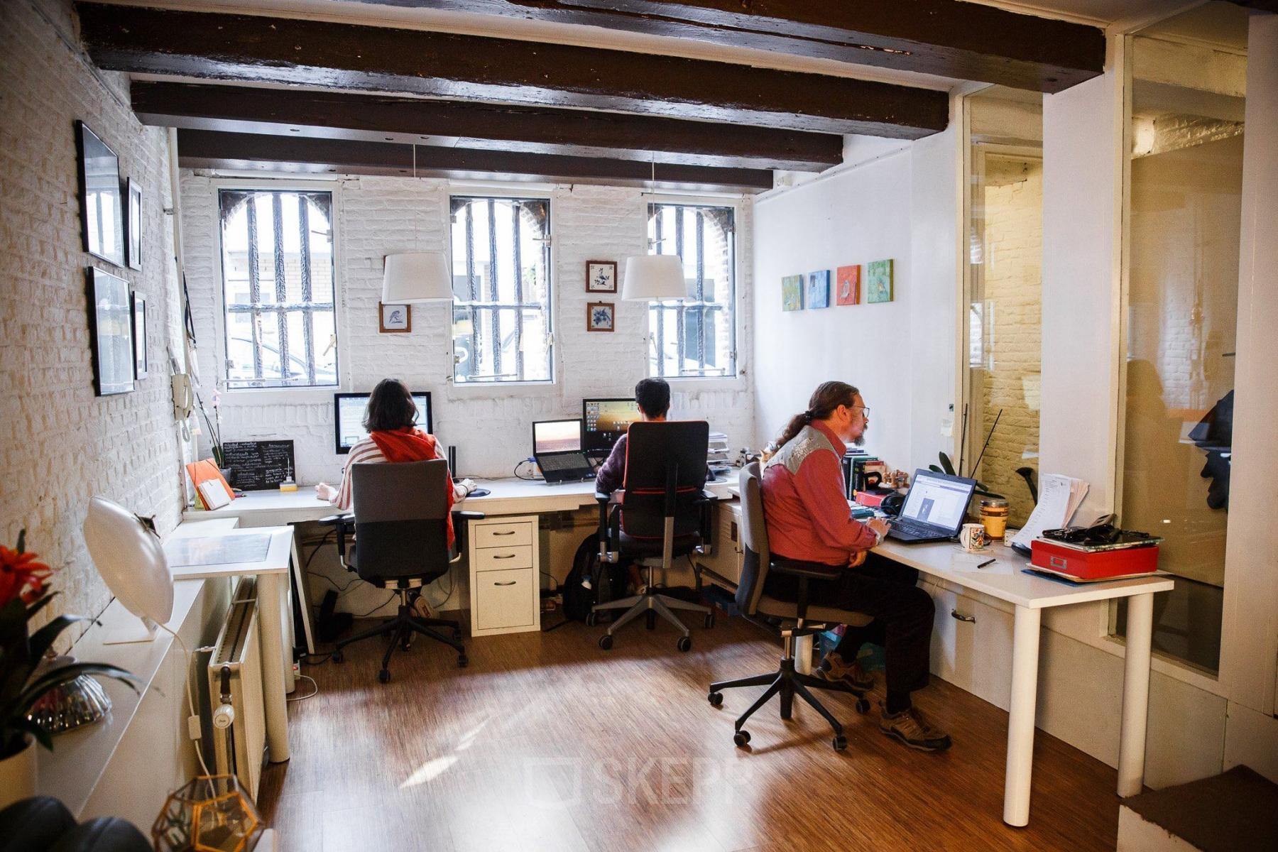 Office space rental at Vinkenstraat 79 HS in Amsterdam Canal Belt showing several people working at desks with computers under exposed beams.