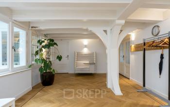 Office space rental at Keizersgracht 452 in Amsterdam Canal Belt, featuring stylish, spacious interior with hardwood floors, white walls, large windows, and cozy seating.