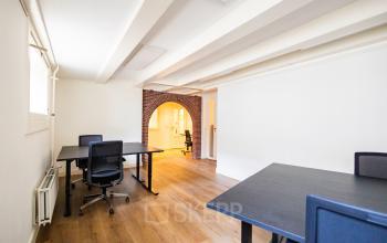 Bright office space rental at Keizersgracht 452, Amsterdam Canal Belt, featuring spacious desks, comfortable chairs, and a charming brick archway.