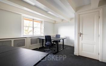 Bright office space with desks and chairs in a room at Keizersgracht 452, Amsterdam Canal Belt, ideal for office space rental with natural light from large windows.
