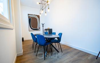 Modern office space with stylish blue chairs around a wooden table, featuring contemporary artwork, located at Keizersgracht 452, Amsterdam Canal Belt, available for office space rental.
