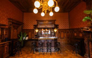 Classic wooden bar interior in a historic building at Keizersgracht 452, Amsterdam Canal Belt, suitable for office space rental. Elegant lighting and intricate woodwork offer a sophisticated ambiance.
