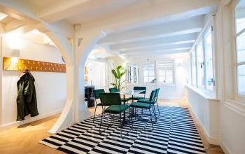 Bright, stylish office space rental at Keizersgracht 452, Amsterdam Canal Belt, featuring modern furnishings, sleek striped rug, and ample natural light, perfect for collaborative work or meetings.