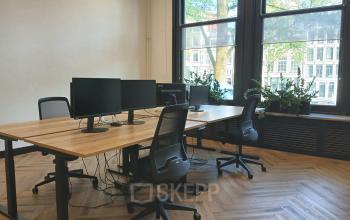 Bright office space with large windows, wooden floors, and modern desks overlooking Amsterdam Canal Belt. Ideal for a productive work environment at Herengracht 320 with office space rental options.