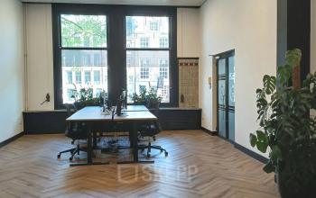 Spacious office for rent at Herengracht 320, Amsterdam Canal Belt, featuring large windows, wooden floors, and modern furnishings ideal for collaborative workspaces.