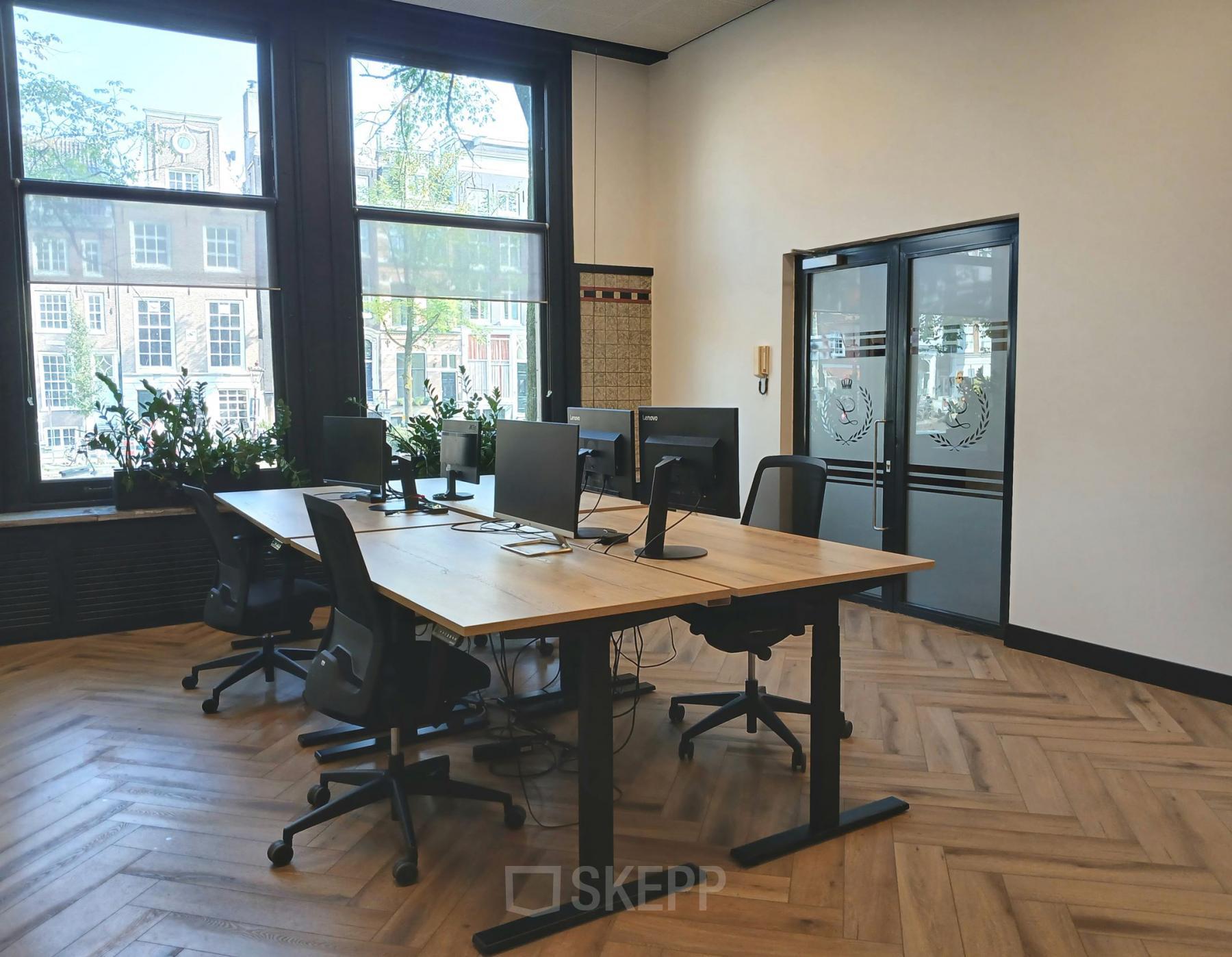 Bright office at Herengracht 320 with wooden floors, modern furniture, and large windows offering views of Amsterdam Canal Belt. Perfect office space rental for productivity.