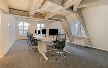 Modern office space in Amsterdam's Canal Belt at Keizersgracht 572. Features spacious workstations under wooden beams, offering a stylish setting for office space rental.