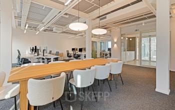Modern office space at Keizersgracht 572 572 in the Amsterdam Canal Belt with sleek wooden communal tables, ergonomic chairs, and multiple workstations. Ideal for those looking to rent office space in a vibrant location.