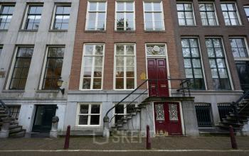 Exterior view of Keizersgracht 391A, featuring classic Amsterdam canal architecture with red doors and large windows. Ideal for businesses seeking office space rental in the vibrant Amsterdam Canal Belt.