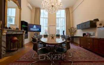 Elegant conference room at Keizersgracht 391A, Amsterdam Canal Belt, featuring a grand chandelier, marble fireplace, and round table. Ideal for office space rental with a touch of sophistication.