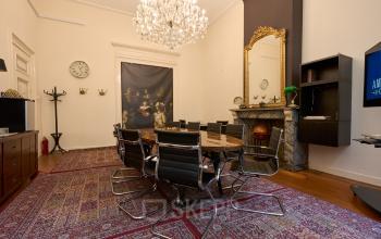Elegant conference room at Keizersgracht 391A in Amsterdam Canal Belt, featuring a large round table, stylish black chairs, a chandelier, and a classic fireplace. Ideal for office space rental.