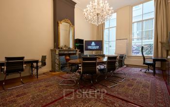Elegant conference room at Keizersgracht 391A, Amsterdam Canal Belt. Features ornate chandelier, classic fireplace, and modern seating, ideal for office space rental with character and charm.