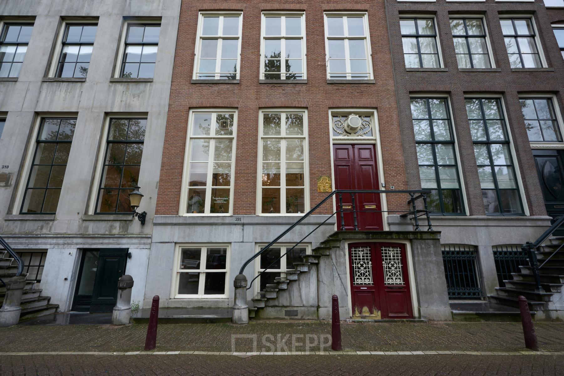 Exterior view of Keizersgracht 391A, featuring classic Amsterdam canal architecture with red doors and large windows. Ideal for businesses seeking office space rental in the vibrant Amsterdam Canal Belt.