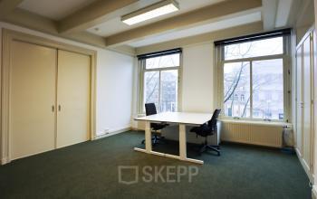Spacious office with large windows at Keizersgracht 261 in Amsterdam Canal Belt, featuring a minimalist setup with two chairs and desk. Ideal for those seeking office space rental with natural light.