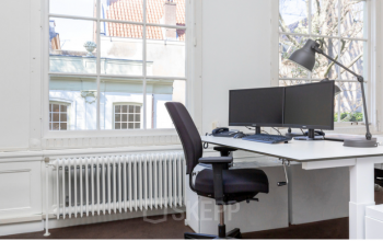Bright office space rental at Keizersgracht 261, Amsterdam Canal Belt, featuring large windows, white walls, desks with computer setups, and a view of traditional Amsterdam architecture.