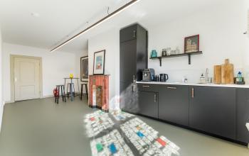 Bright interior space with modern black kitchenette, counter seating, and colorful floor patterns. Suitable for office space rental at Keizersgracht 261, Amsterdam Canal Belt.