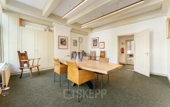 Furnished office space for rent at Keizersgracht 261, Amsterdam Canal Belt, featuring a spacious meeting area with a large wooden table and chairs, ideal for office space rental.