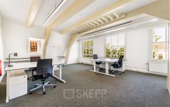 Bright office space rental at Keizersgracht 261, Amsterdam Canal Belt, featuring desks and chairs with natural light pouring in.