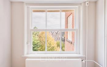 Bright office space rental at Herengracht 582-584 in Amsterdam Canal Belt, featuring a large window with a view of the historic cityscape.