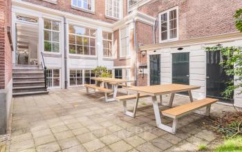 Exterior view of Herengracht 582-584 office showing a courtyard with picnic tables, ideal for breaks in the Amsterdam Canal Belt.
