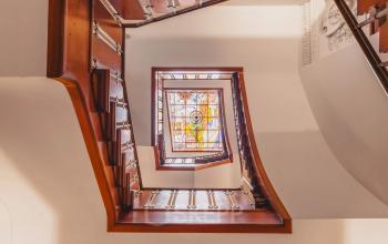 Spiral staircase with wooden railings and colorful stained glass window at Herengracht 582-584, Amsterdam Canal Belt, perfect for office space rental ambiance.